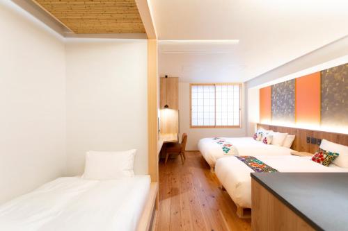 een kamer met 2 bedden en een bank bij Hotel Kanazawa Zoushi in Kanazawa