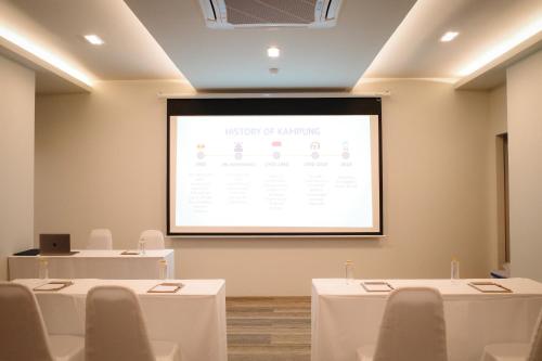 a lecture room with two tables and a projection screen at The Rise Suites Hotel, Chiang Mai - SHA Extra Plus in Chiang Mai