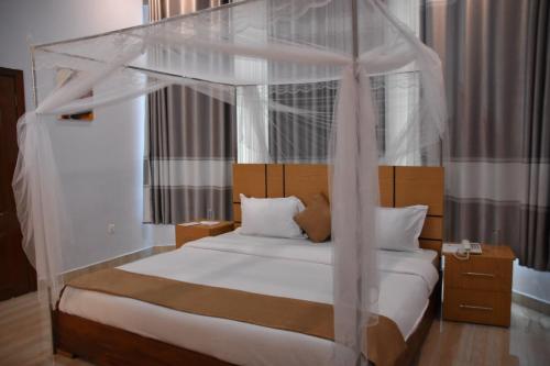 a bedroom with a canopy bed with white sheets and pillows at Chimpanzee Lodge in Rwumba