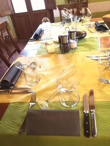 a table with a green table cloth with glasses and silverware at Locanda Vesuna Hotel Countryhouse in Pienza