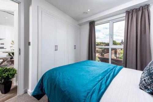 um quarto com uma cama com um cobertor azul em A beautiful brand new flat 25-minute to London em Luton