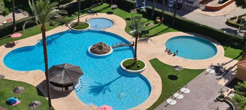 una vista aérea de 2 piscinas con sombrilla en Apartamentos Florazar II, en Cullera