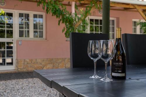 Quinta Aida Cottage and B&B Suites في لاغوا: كأسين من النبيذ وزجاجة من النبيذ على طاولة