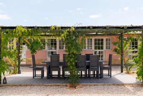 een tafel en stoelen onder een pergola voor een huis bij Quinta Aida Cottage and B&B Suites in Lagoa