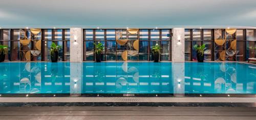 a swimming pool with plants on the side of a building at Mövenpick Living West Hanoi in Hanoi