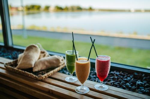 três copos de vinho sentados numa mesa com bolos em Hestia Hotel Haapsalu SPA em Haapsalu