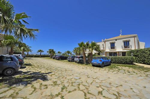 a street with parked cars and a building and palm trees at Resort Santa Maria Hotel in Birgi Vecchi
