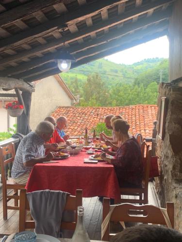 grupa ludzi siedzących przy stole jedzących jedzenie w obiekcie Posada El Pareón w mieście Sirviella