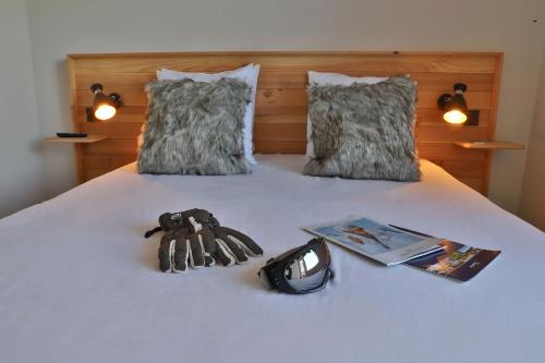 a bed with a pair of gloves and a book at SOWELL Family La Lauzière in Aime La Plagne