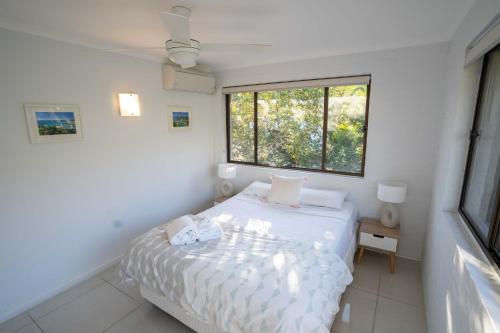 a white bedroom with a bed and a window at Myuna Holiday Apartments in Noosa Heads