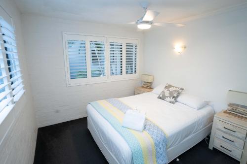 a white bedroom with a bed and a window at Myuna Holiday Apartments in Noosa Heads