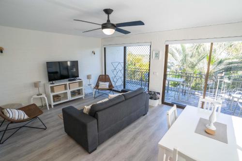 a living room with a couch and a tv at Myuna Holiday Apartments in Noosa Heads
