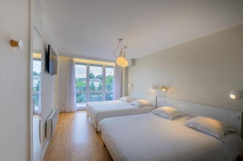 two beds in a room with two windows at Hôtel Vulcain in LʼHorme