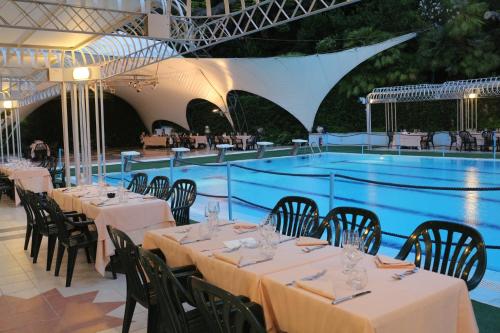 a restaurant with tables and chairs next to a swimming pool at Hotel Mirasole International in Gaeta