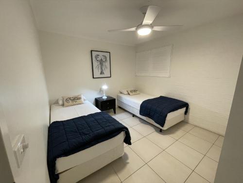 a bedroom with two beds and a ceiling fan at Myuna Holiday Apartments in Noosa Heads
