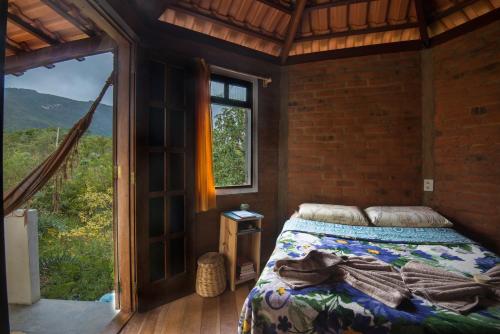 a bedroom with a bed and a large window at Hospedagem Sabor Da Trilha in Vale do Capao