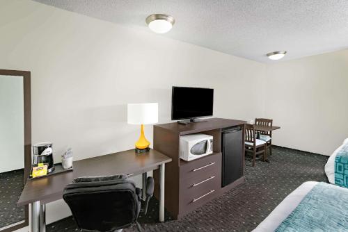 a hotel room with a desk with a microwave and a tv at Howard Johnson by Wyndham Gananoque in Gananoque
