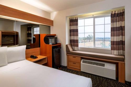 a hotel room with a bed and a window at Microtel Inn & Suites by Wyndham Salt Lake City Airport in Salt Lake City