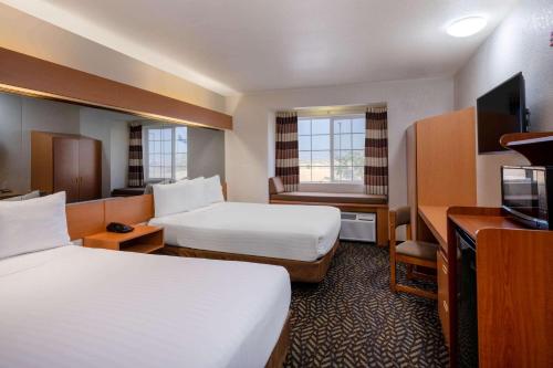 a hotel room with two beds and a television at Microtel Inn & Suites by Wyndham Salt Lake City Airport in Salt Lake City