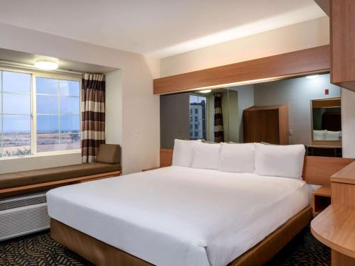 a hotel room with a large bed and a window at Microtel Inn & Suites by Wyndham Salt Lake City Airport in Salt Lake City