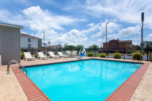 une grande piscine avec des chaises et une clôture dans l'établissement La Quinta by Wyndham Oxford - Anniston, à Oxford