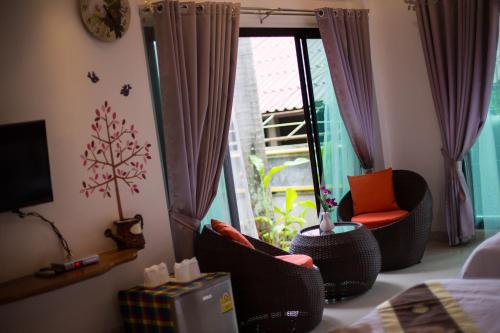 a room with a bed and chairs and a window at Is Am O Chiang Mai Resort in San Sai