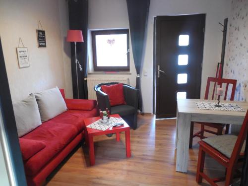 a living room with a red couch and a table at Ferienwohnungen 20er in Byhleguhre-Byhlen