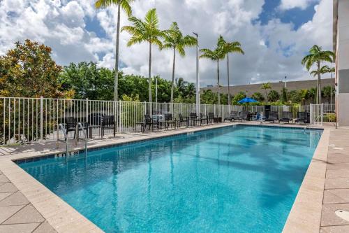 a swimming pool with blue water and palm trees at Comfort Suites Fort Lauderdale Airport & Cruise Port in Dania Beach