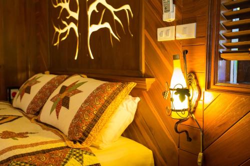 a bedroom with a bed with a light on the wall at Is Am O Chiang Mai Resort in San Sai