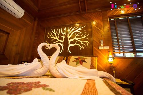 two white swans are sitting on a bed at Is Am O Chiang Mai Resort in San Sai
