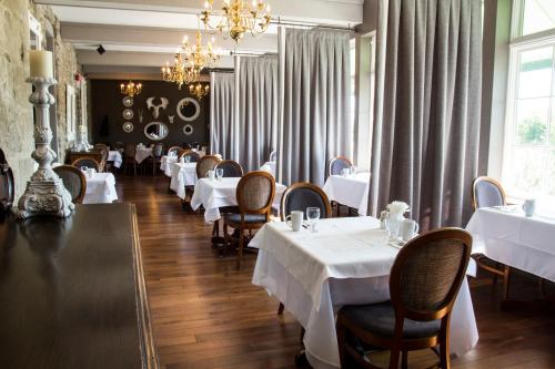a restaurant with white tables and chairs and a chandelier at Old Stone Inn Boutique Hotel in Niagara Falls