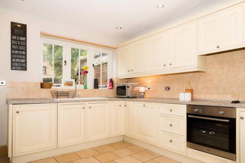 a white kitchen with white cabinets and a microwave at Piper Cottage, Bilbrough, York in Bilbrough