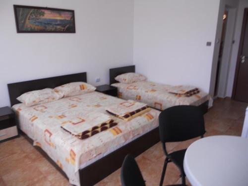 a bedroom with two beds and a table and chairs at "Aхтополис" - подсигурено безплатно паркиране in Ahtopol