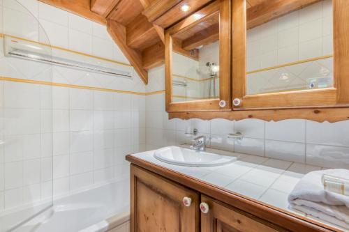 a bathroom with a sink and a tub at Residence Les Fermes du Soleil - maeva Home in Les Carroz d'Araches