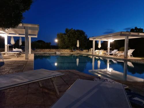 a swimming pool at night with a table and chairs at Casetta Letizia in Ostuni