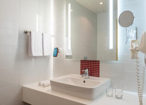 a white bathroom with a sink and a mirror at Park Inn by Radisson Volgograd in Volgograd