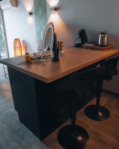 a kitchen island with a wooden counter and a bottle of wine at La Ronde des Bois - Romance et Bien Être - Jacuzzi privatif-piscine-patio in Mellecey