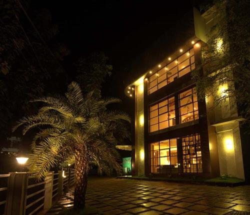 MattanūrにあるHOTEL LA SERENE Mattannurの夜の建物前のヤシの木