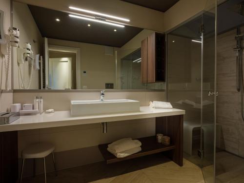 a bathroom with a sink and a glass shower at Parc Hotel Germano Suites & Apartments in Bardolino