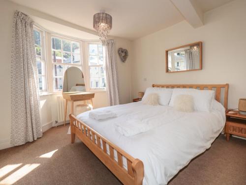 a bedroom with a large bed with white sheets at Nookie Cottage in Dartmouth