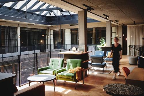 a woman walking through a restaurant with chairs and tables at Hotel Gilbert in Vienna