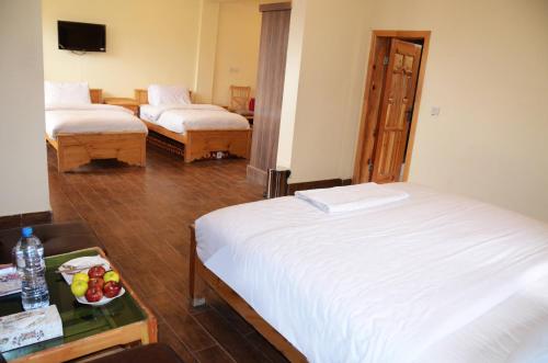 a hotel room with two beds and a bowl of fruit on a table at Karakorum View Hotel Karimabad Hunza in Hunza
