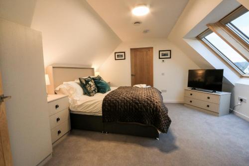 a attic bedroom with a bed and a television at Black Barn Skye - Contemporary 3 bed / 4 bath home in Broadford