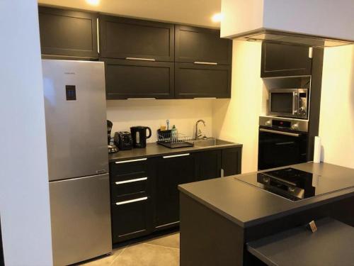 une cuisine avec des armoires noires et un réfrigérateur en acier inoxydable dans l'établissement LOFT Tignes Val Claret, à Tignes