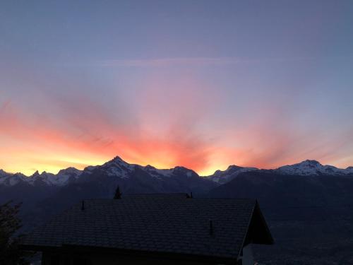 a sunset over a mountain range with a house at Le Coin Barlouka in Veysonnaz