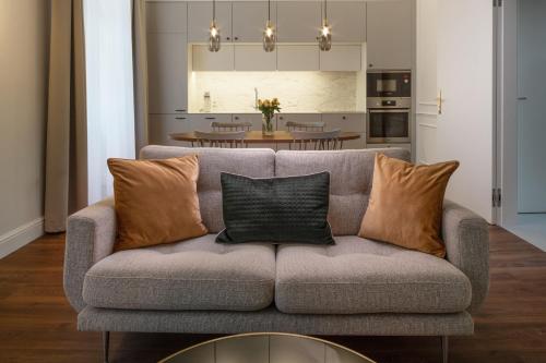 a living room with a gray couch with pillows at OREA Place Seno in Prague