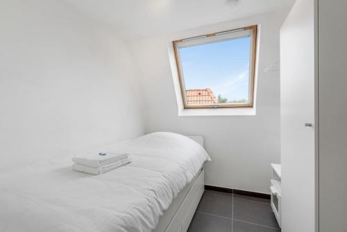 um quarto branco com uma cama e uma janela em Walhofpark 24 em De Panne