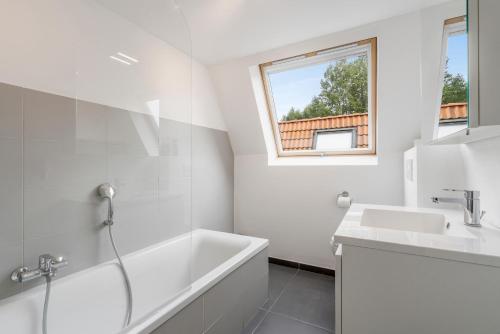 een witte badkamer met een bad en een wastafel bij Walhofpark 24 in De Panne