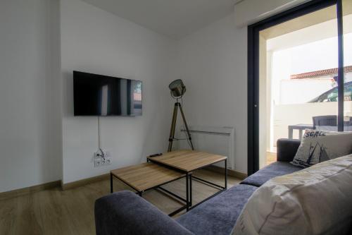 un salon avec un canapé, une table et une télévision dans l'établissement Appartement neuf, 150m de la grande plage, parking, proche commerces, à Saint-Gilles-Croix-de-Vie