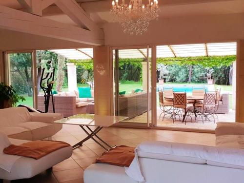 Elle comprend un salon doté d'un mobilier blanc et d'une table en verre. dans l'établissement Villa raffinée à Orange avec piscine privée, à Orange